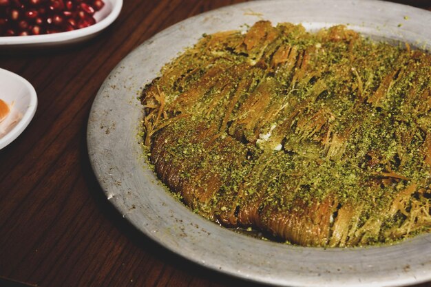 Dessert turc kunefe kunafa kadayif avec de la poudre de pistache et du fromage chaud mangé un bonbon