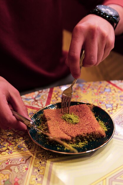 Dessert turc kunefe, kunafa, kadayif avec de la poudre de pistache et du fromage chaud mangé un bonbon