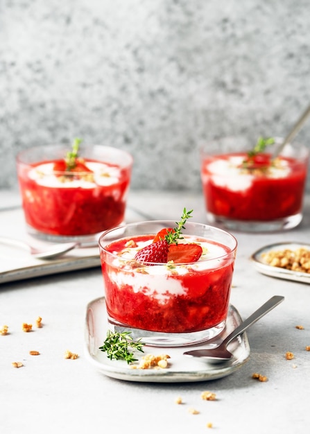 Dessert végétarien à la crème de fruits avec purée de fraises, yaourt et granola dans des bols en verre