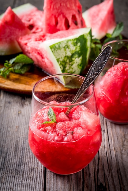 Photo desserts aux fruits d'été, cocktails surgelés. glace granit de pastèque à la menthe, en verres portionnés, avec des tranches de pastèque.