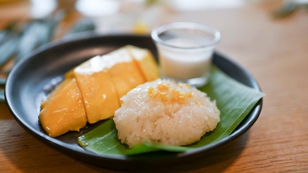 Desserts sucrés traditionnels thaïlandais Mangue avec riz gluant sur une assiette noire Desserts de saison asiatiques