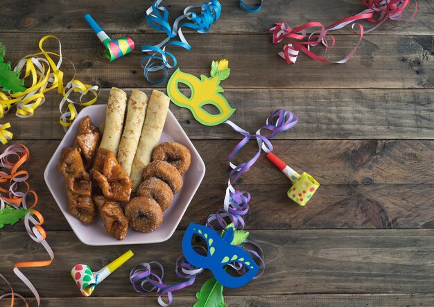 Des desserts typiques du carnaval avec des décorations de carnaval sur un fond en bois