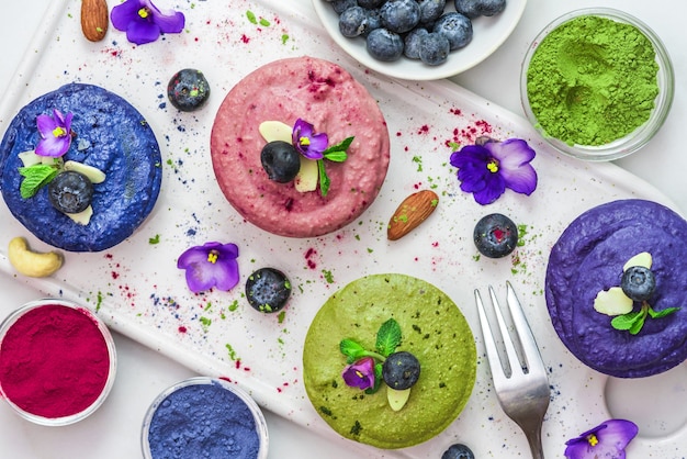 Desserts végétaliens sains. assortiment de gâteaux de noix de cajou crus avec matcha, acai, myrtille, menthe, noix et fleurs. régime sans gluten. vue de dessus. pose à plat