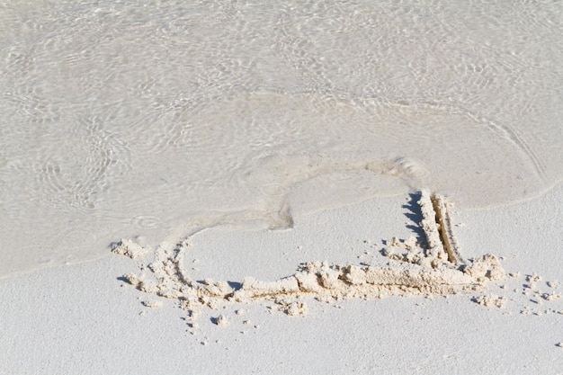 Dessin de coeur sur la plage avec vague.