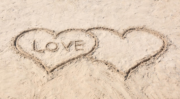 Dessin de coeurs avec le mot AMOUR sur le concept de mariage de plage de sable