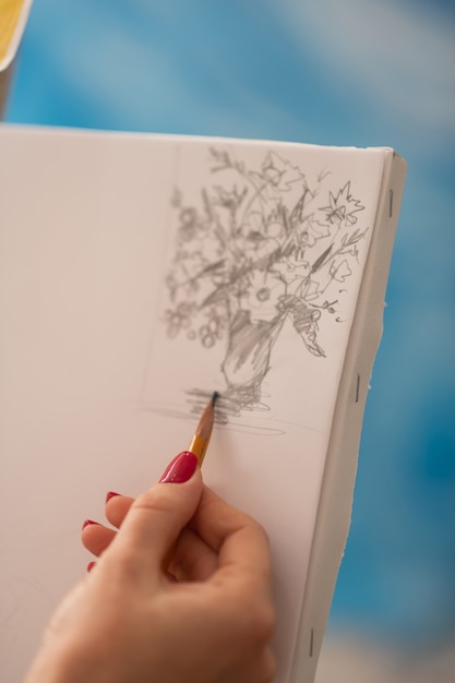 Dessin de fleurs. Gros plan d'un artiste prometteur avec des ongles rouges dessin vase avec des fleurs