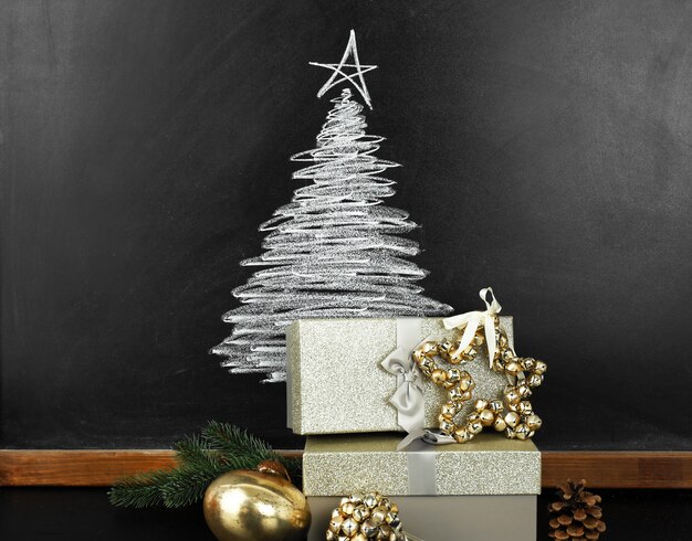 Dessin de sapin sur tableau noir et beaux cadeaux. Fond de Noël