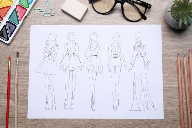 Dessin de vêtements élégants et d'autres fournitures de créateurs de mode sur une table en bois.