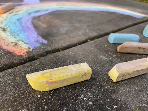 Photo des dessins d'arc-en-ciel d'enfants par des craies colorées sur l'asphalte un jour d'été ensoleillé