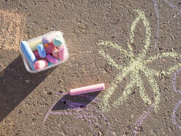 Dessins d'enfants à la craie sur le trottoir et à la craie éparpillée