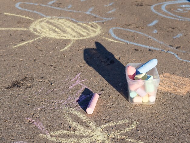 Dessins d'enfants à la craie sur le trottoir et à la craie éparpillée