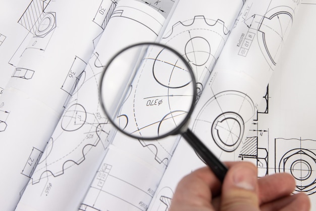 Dessins techniques de pièces et de mécanismes industriels à travers une loupe