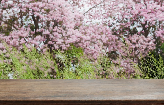 Dessus de table en bois et arbre fleur floue dans le fond de jardin avec filtre vintage