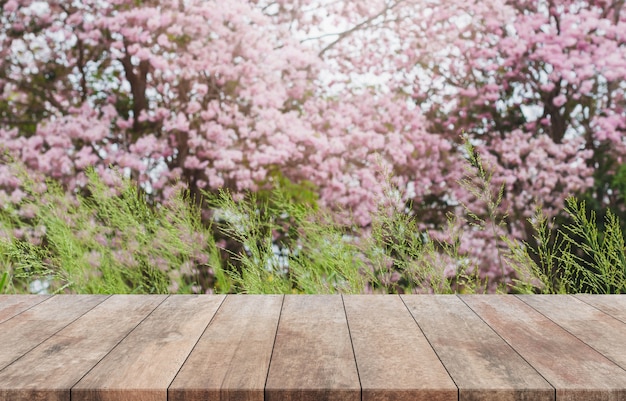 Dessus de table en bois et arbre fleur floue dans le fond de jardin avec filtre vintage