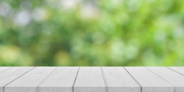 Dessus de table en bois blanc vide avec arrière-plan flou vert bokeh.