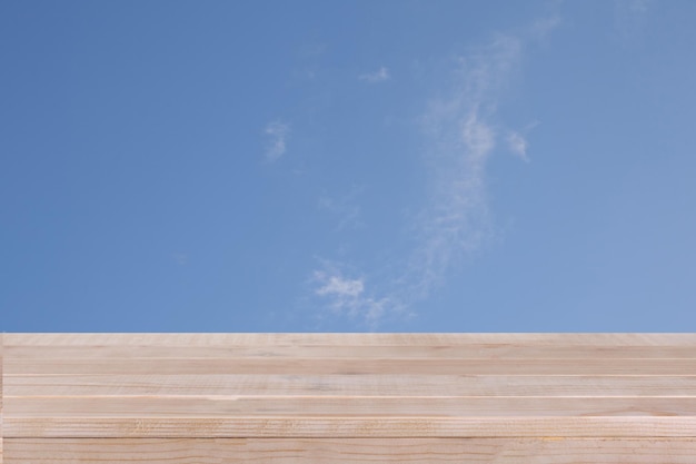 Le dessus de table en bois brun sur le ciel bleu avec le fond de nuage peut être employé pour le montage