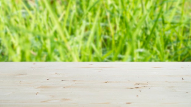 Un dessus de table en bois clair avec espace de copie pour l'installation d'un produit ou d'une mise en page sur un fond avec de l'herbe verte en flou