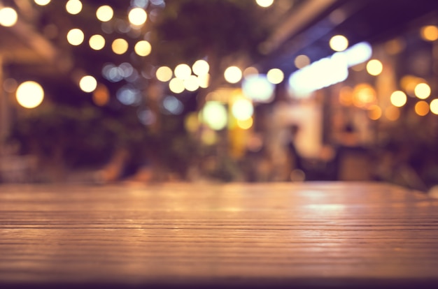 Dessus de table en bois avec flou d'éclairage dans un café-restaurant de nuit