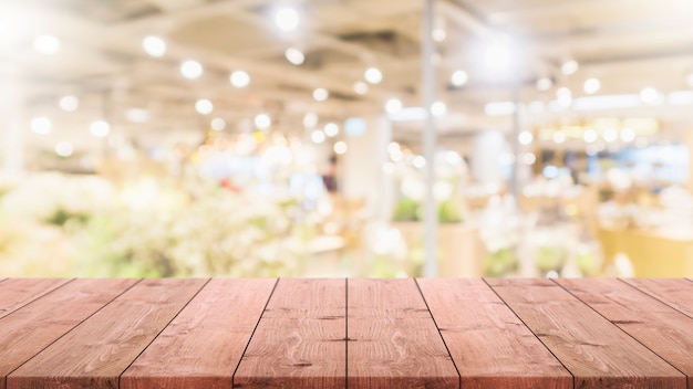 Dessus de table en bois vide sur floue avec fond de centre commercial bokeh.