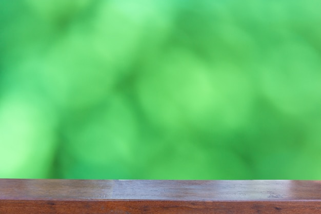 Dessus de table en bois vide sur fond abstrait bokeh vert flou