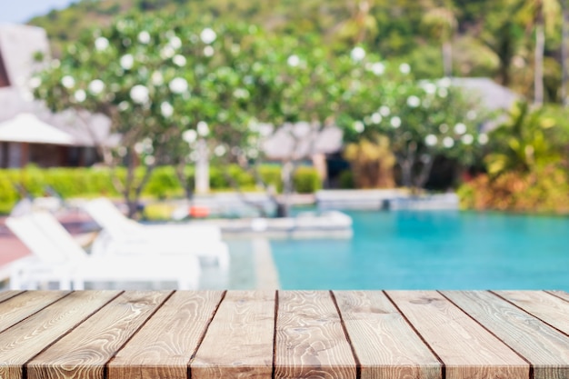 Photo dessus de table en bois vide et piscine floue dans une station balnéaire tropicale sur fond de bannière d'été - peuvent être utilisés pour afficher ou monter vos produits.