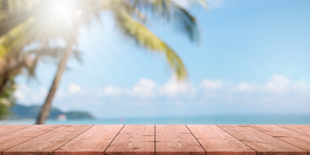 Dessus de table en bois vide et plage floue de l&#39;été avec fond de bannière de mer et ciel bleu.