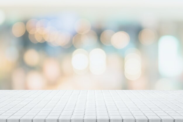 Dessus de table en mosaïque de céramique blanche vide et arrière-plan flou de café et de restaurant bokeh.