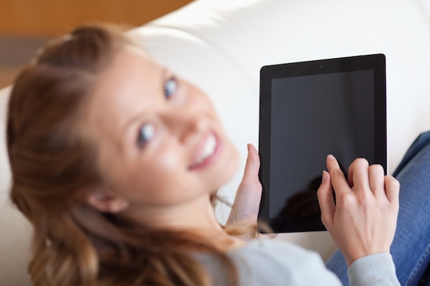 Dessus de vue de femme souriante avec tablette sur le canapé