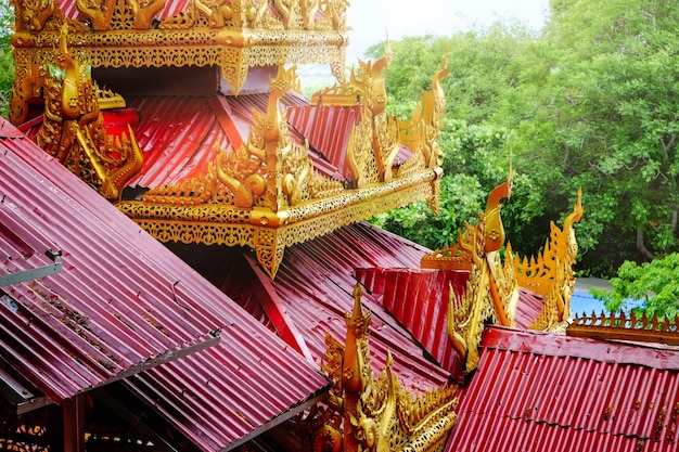 Détail architectural des toits colorés de rouge et d'or sur un temple à Mandalay