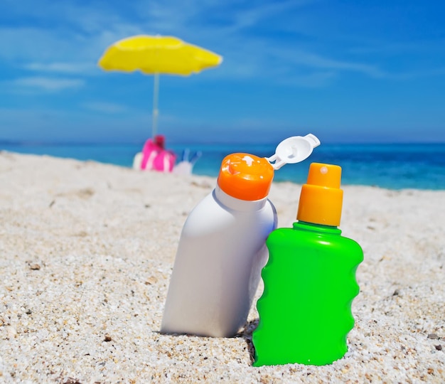 Détail de deux bouteilles de crème solaire sur le sable