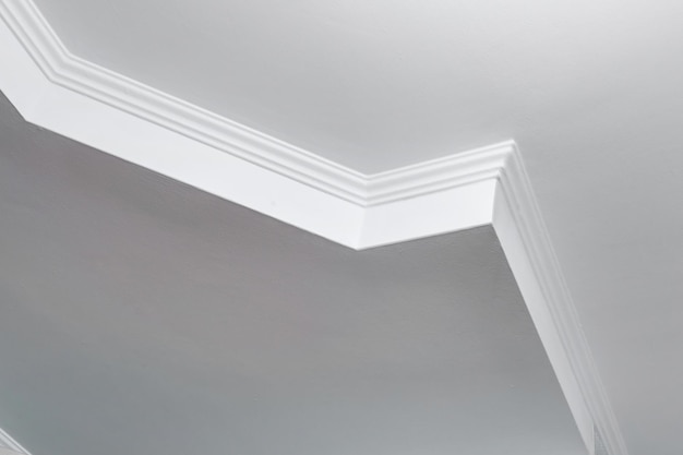 Détail du plafond d'angle avec moulures complexes Plafond suspendu et construction de cloisons sèches dans une pièce vide d'un appartement ou d'une maison Plafond tendu blanc et de forme complexe