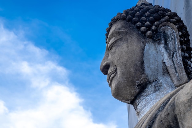 Détail du visage d'une représentation du bouddha les yeux fermés sur fond de ciel bleu nature la vue de dessous