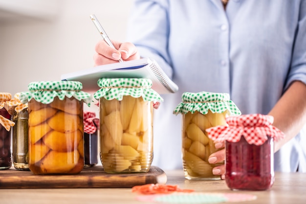 Photo détail de fruits confits faits maison avec une femme écrivant la recette.