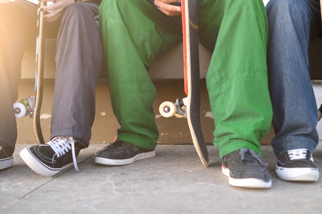 Détail d'un groupe de jeunes patineurs assis avec leurs planches à roulettes dans un skate park