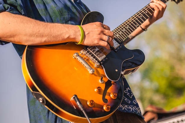 Détail d'une guitare électrique colorée tenue par un musicien la jouant