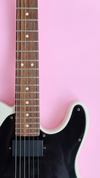 Détail de la guitare électrique sur un fond rose