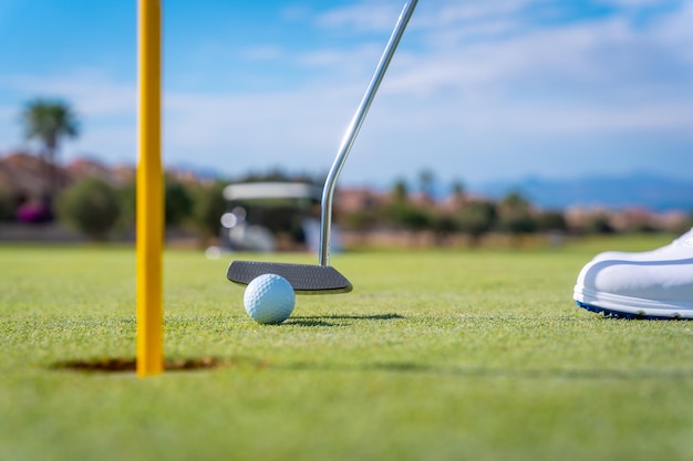 Détail d'un homme jouant au golf mettant la balle dans le trou sur le green avec le putter