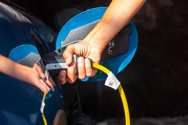 Détail d'une main tenant une voiture électrique chargeant les batteries dans le garage de la maison pas d'essence