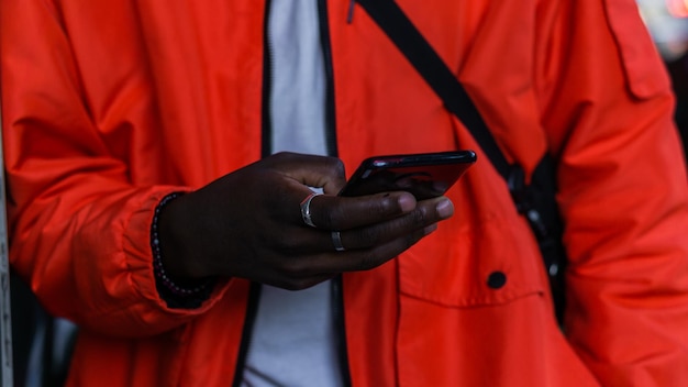 Détail des mains d'un homme africain méconnaissable tenant un téléphone portable.