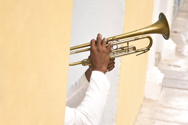 Photo détail des mains de musicien cubain jouant de la trompette dans la rue colorée de la havane, cuba