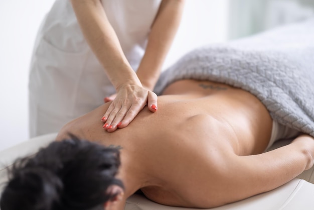 Détail d'une masseuse offrant un massage à une cliente sur sa lame sholder