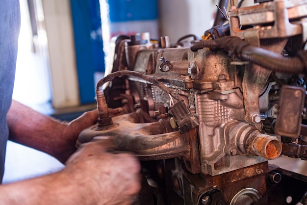 Détail de mécanicien révise le moteur de voiture dans un atelier