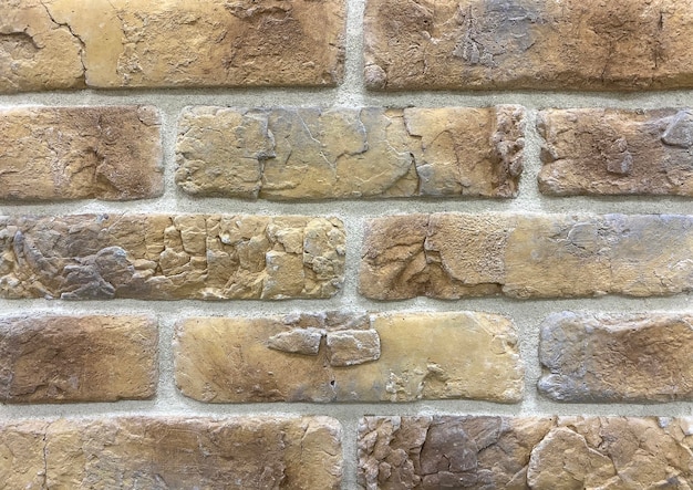 Détail d'un mur fait de carreaux décoratifs en pierre beige et coutures grises pour la décoration murale
