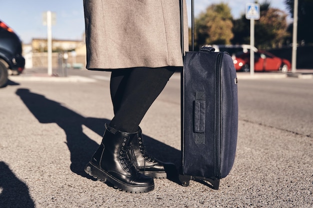 Photo détail de la partie inférieure d'une femme d'affaires avec un bagage à main en attente d'un véhicule sur l'autoroute