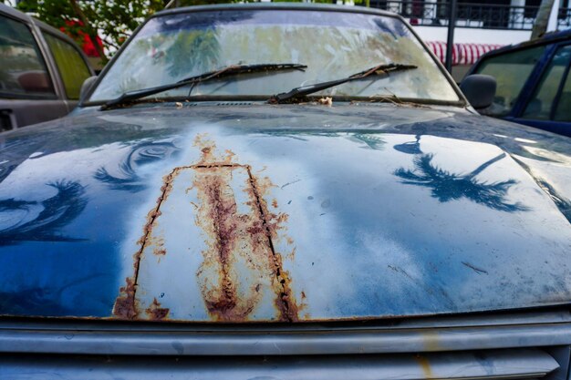 Photo détail de la peinture fissurée et rouillée du capot avant de la voiture