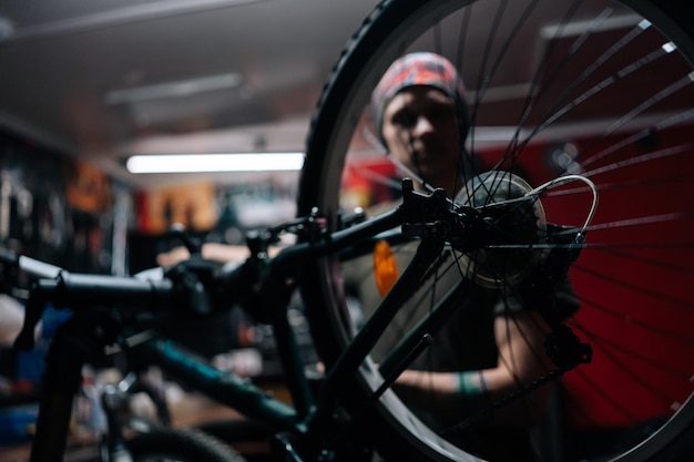 Détail photo recadrée d'un mécanicien flou méconnaissable réparant un vélo à l'aide d'un outil spécial travaillant dans un atelier de réparation de vélos avec un intérieur sombre