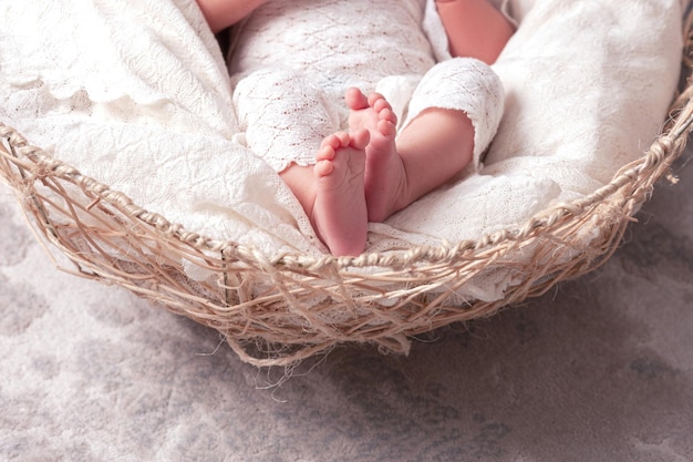 Détail d'un pied de bébé nouveau-né avec une couverture blanche douce Gros plan photo de pieds de bébé nouveau-né sur un plaid tricoté