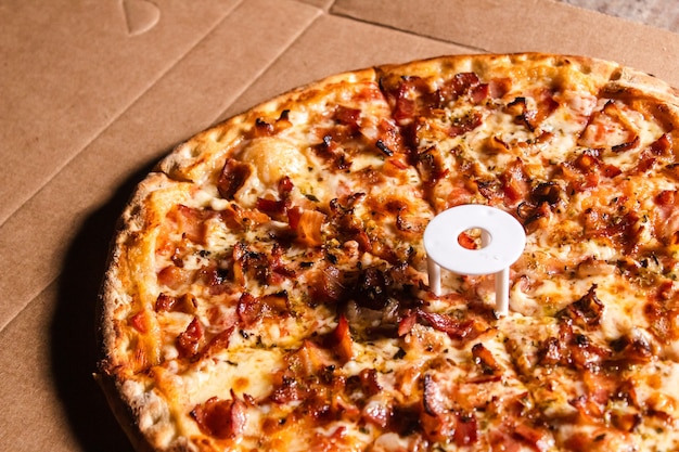 Détail d'une pizza au bacon sur une table en bois.