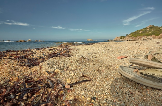 Détail d'une plage méditerranéenne pendant l'été avec une paire de tongs