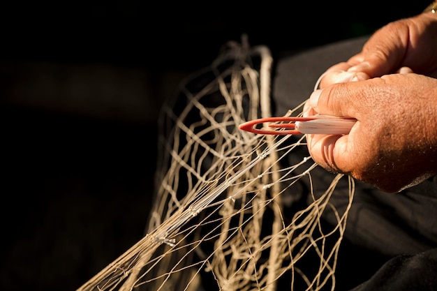 détail tiré du filet de pêche et de l'aiguille dans les mains du pêcheur